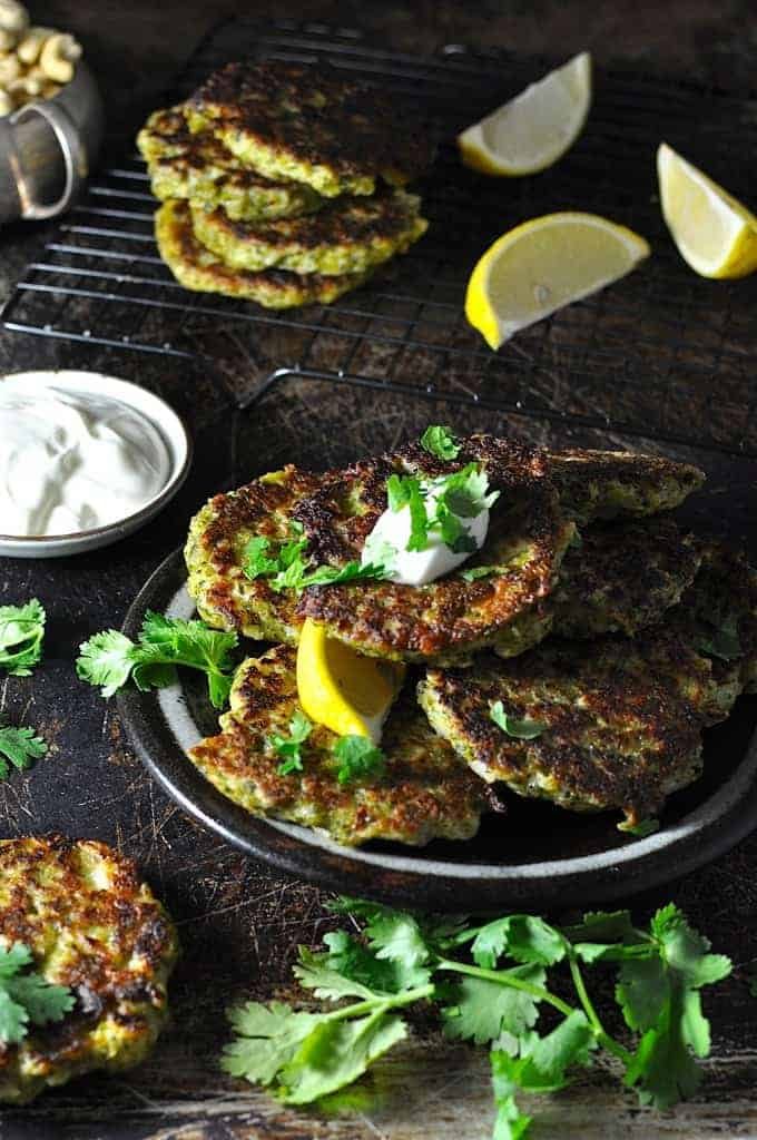 Broccoli Fritters on a plate with lemon wedge and yoghurt sauce