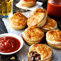 A stack of Party Pies on baking paper with tomato sauce (ketchup)