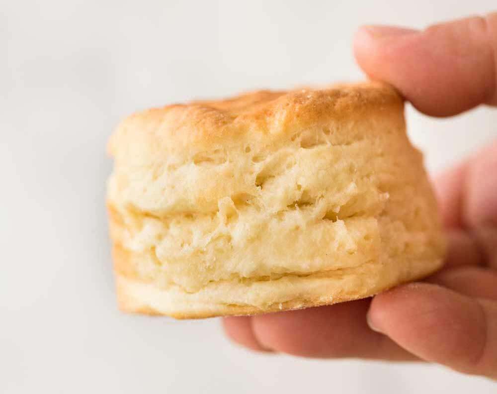 Close up of a plain golden scone being held by fingers.