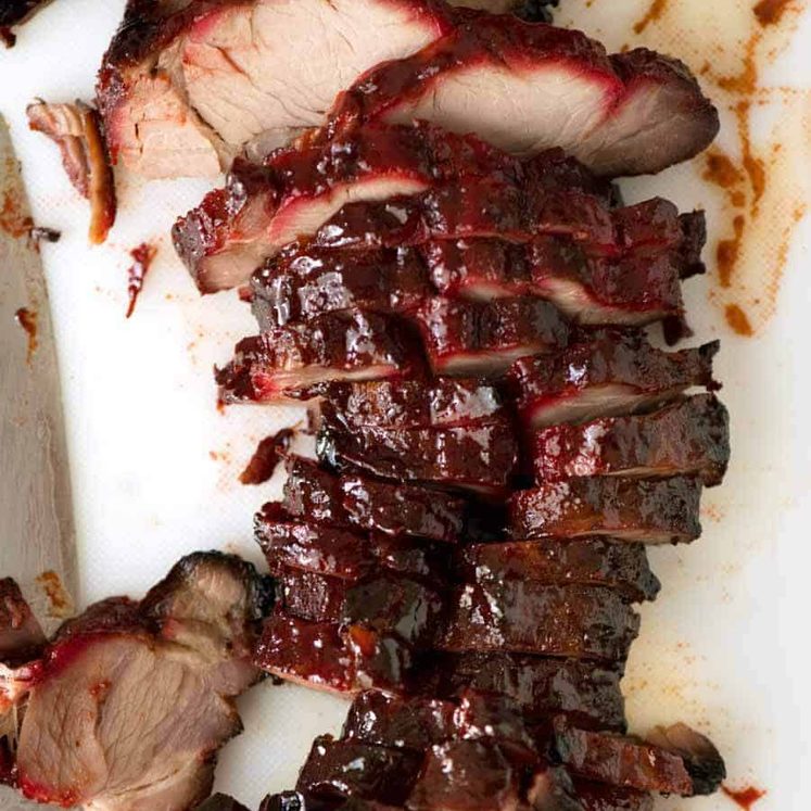 Overhead photo of Char Siu (Chinese Barbecue Pork) sliced on a white cutting board.