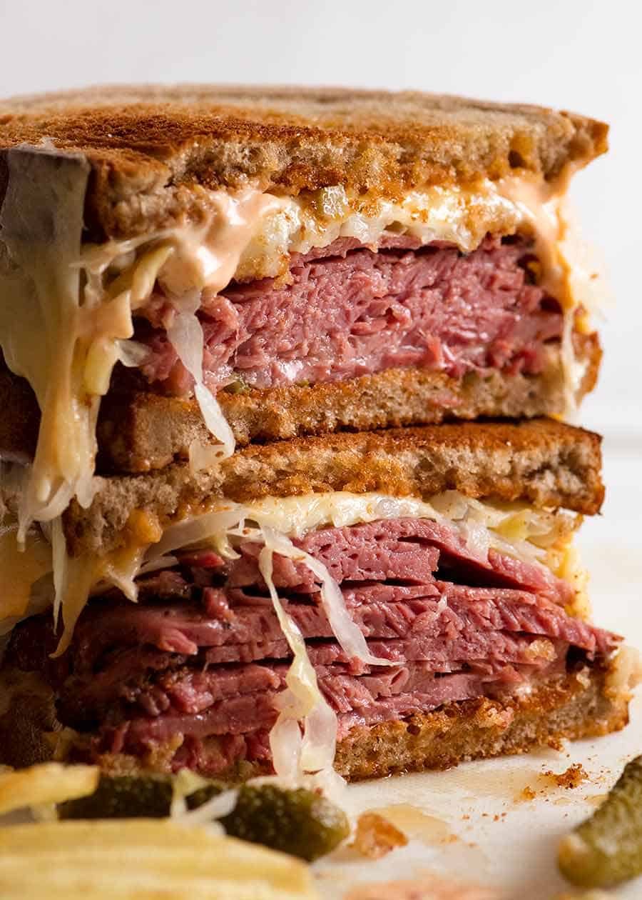 Reuben Sandwich loaded with homemade pastrami, easy quick sauerkraut, Russian Dressing, Swiss cheese on rye bread, ready to be eaten. Katz's deli copycat recipe.