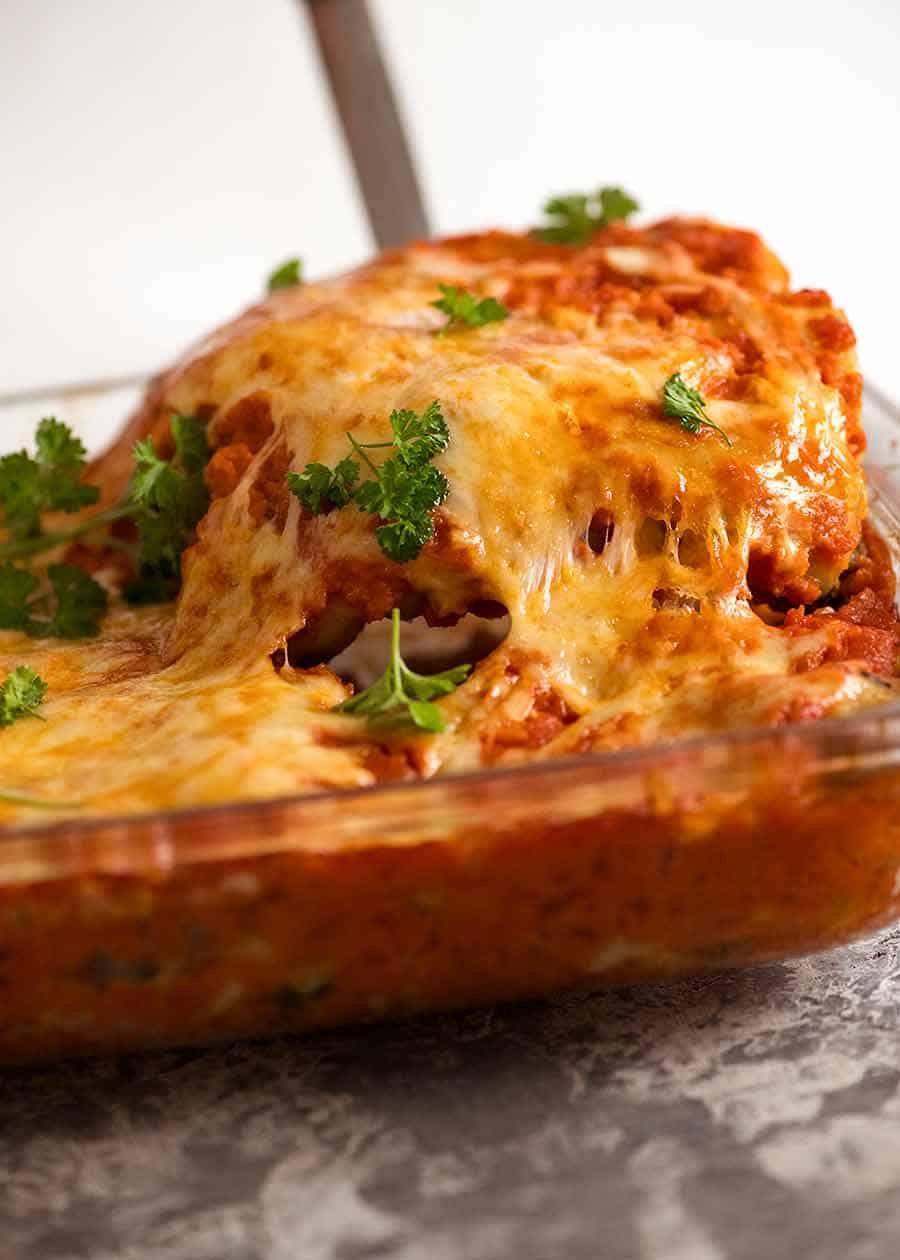 Cheese pull shot serving Spinach Beef Cannelloni from baking dish, fresh out of the oven