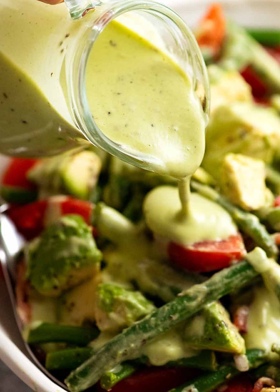 Pouring Creamy Avocado Dressing over green bean salad