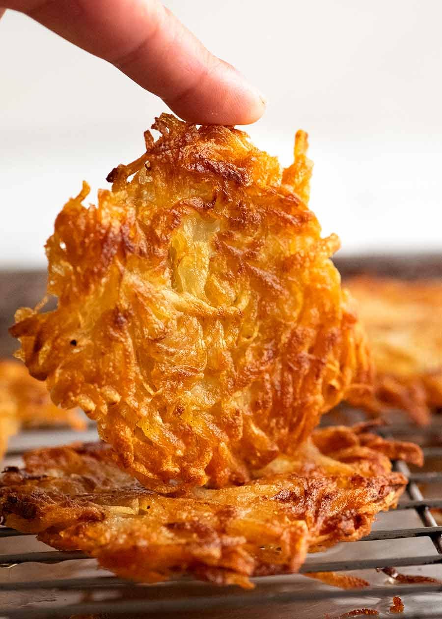 Finger holding Potato rosti on side to show how crispy it is
