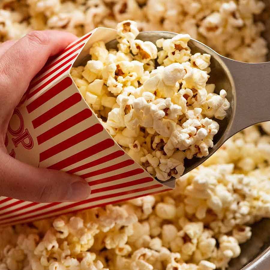 Scooping Slightly sweet and salty butter popcorn into popcorn holder