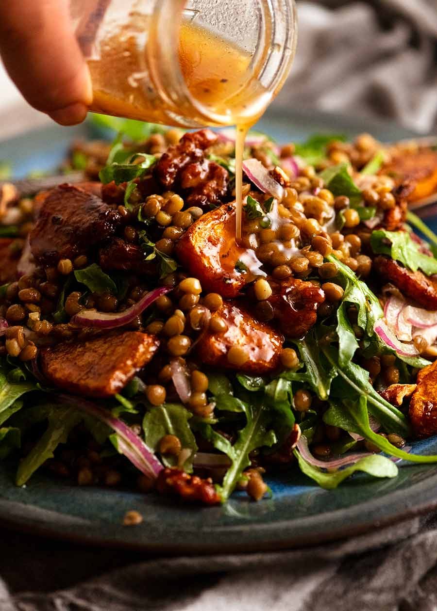 Pouring dressing over Honey Cinnamon Pumpkin Lentil Salad