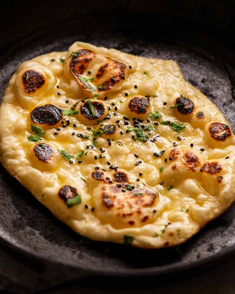 Fluffy chewy naan in a skillet, fresh off the stove