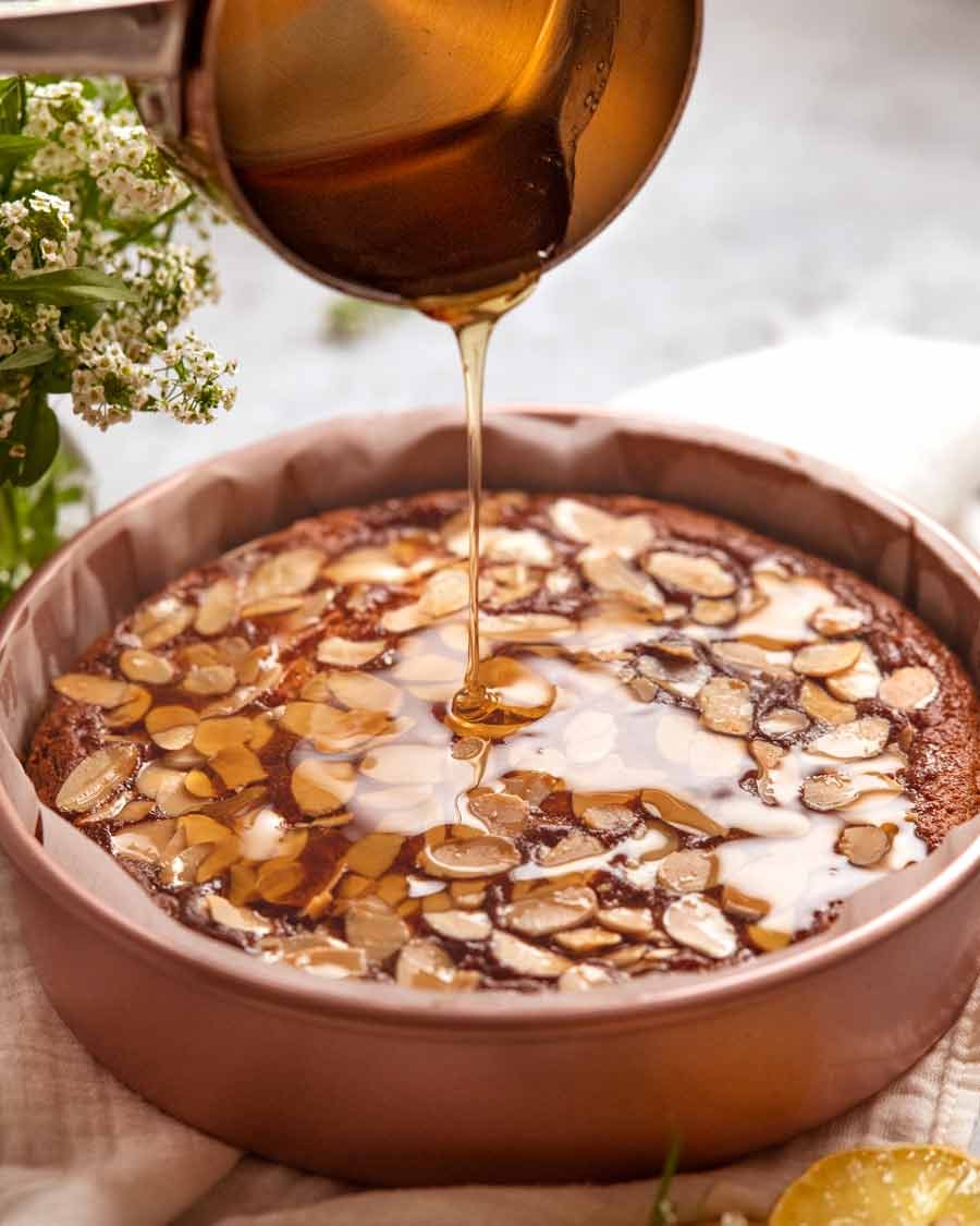 Drizzling honey syrup onto honey cake